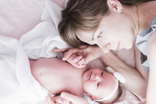 תינוקת מונחת על המיטה ליד אימה